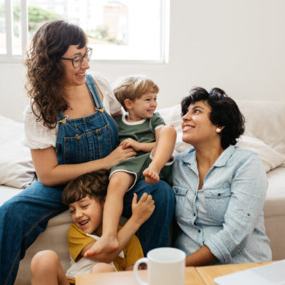 Happy lesbian couple playing with their children at home. Beautiful family of four having great time together indoors.